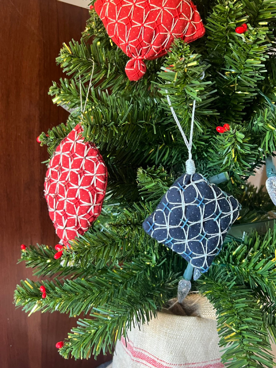 Decorative Christmas ornaments on a tree with a red heart ornament in the background.