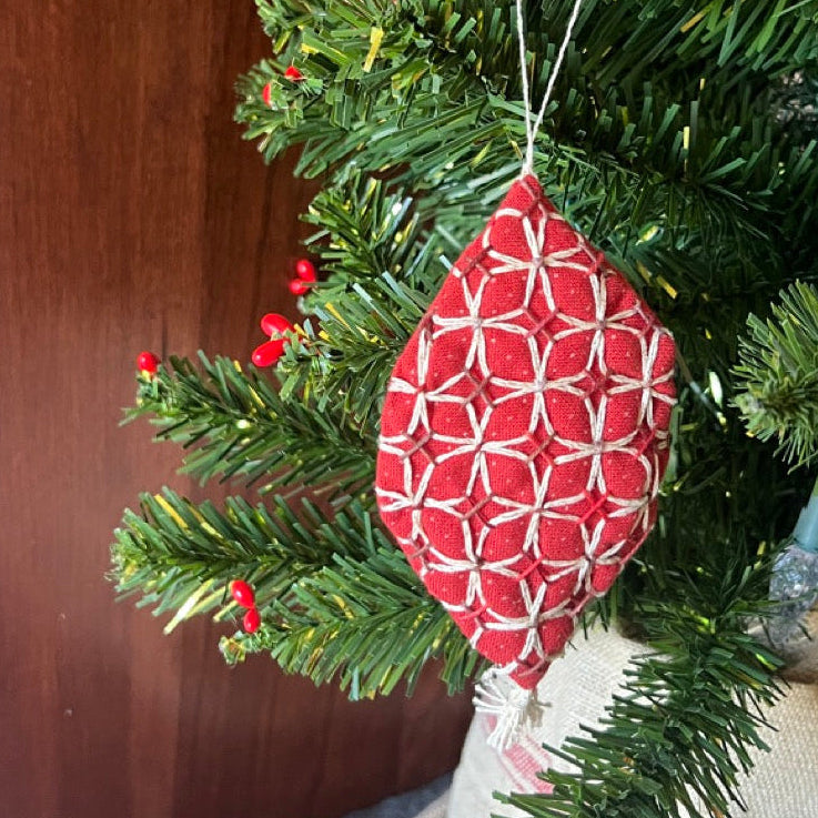Red geometric-patterned ornaments on a Christmas tree with a wooden wall background