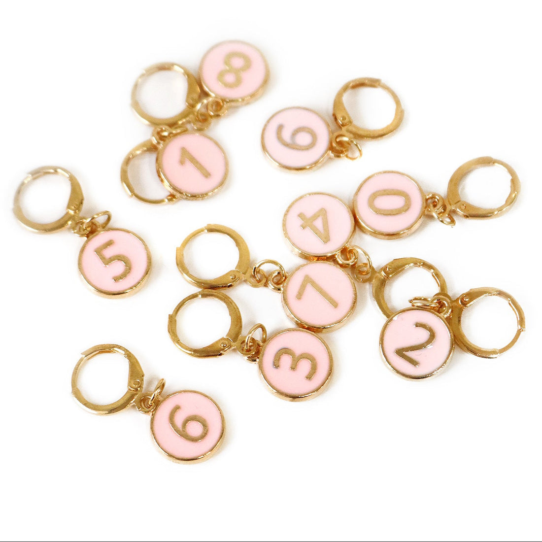 Pink number charms with gold rings on a white background